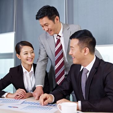Three business professionals smiling and discussing charts in a meeting.