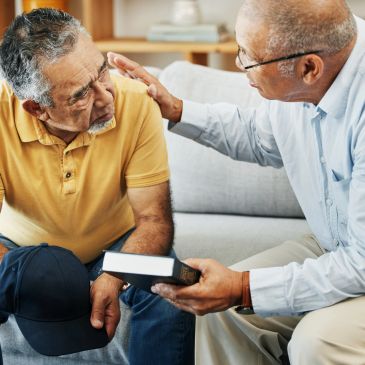 Two elderly men sharing a comforting moment with a book.