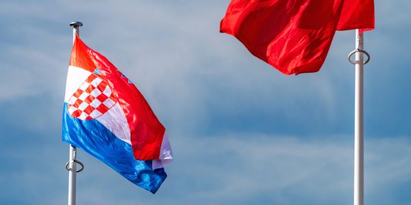 Croatian and Turkish flags waving against a blue sky.