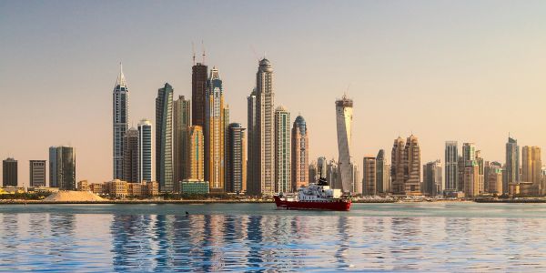 City skyline with modern skyscrapers and a boat on water.