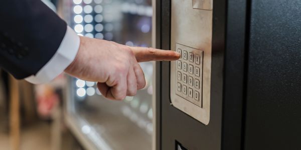 A man in a suit presses a button on a vending machine keypad.