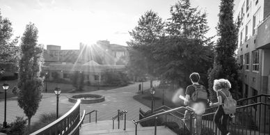 Two students walking up stairs on a college campus at sunrise.