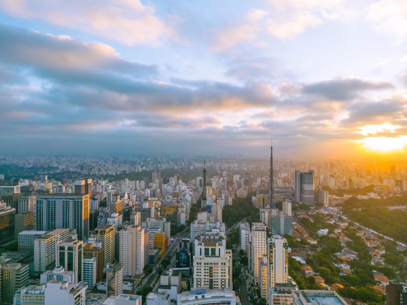 Sunset in the city with buildings and next to a neighborhood with houses and a green park