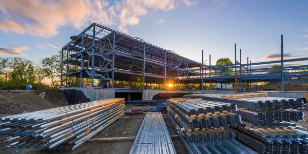 Steel framework of a building under construction at sunset.