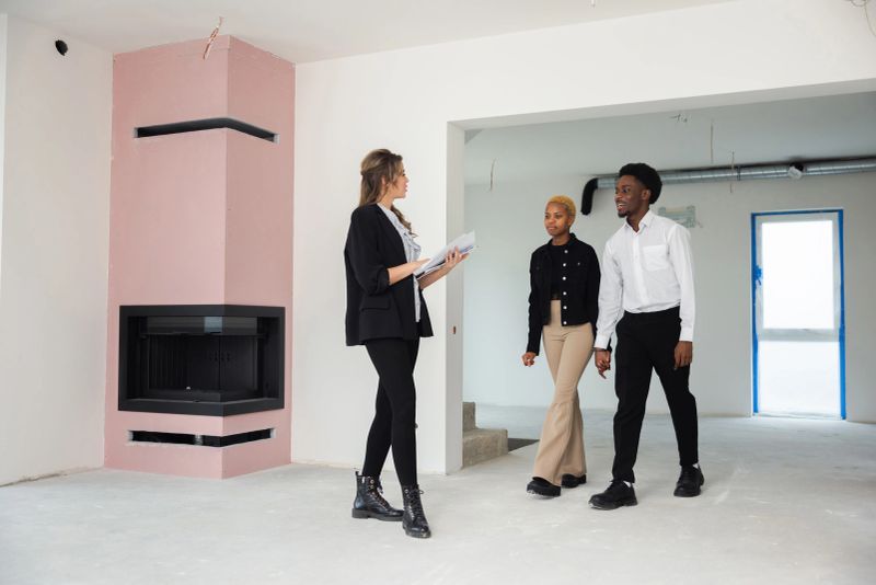 Knowledgeable real estate agent is showing off a gorgeous house to an African couple, equipped with a detailed floor plan for optimal viewing.
