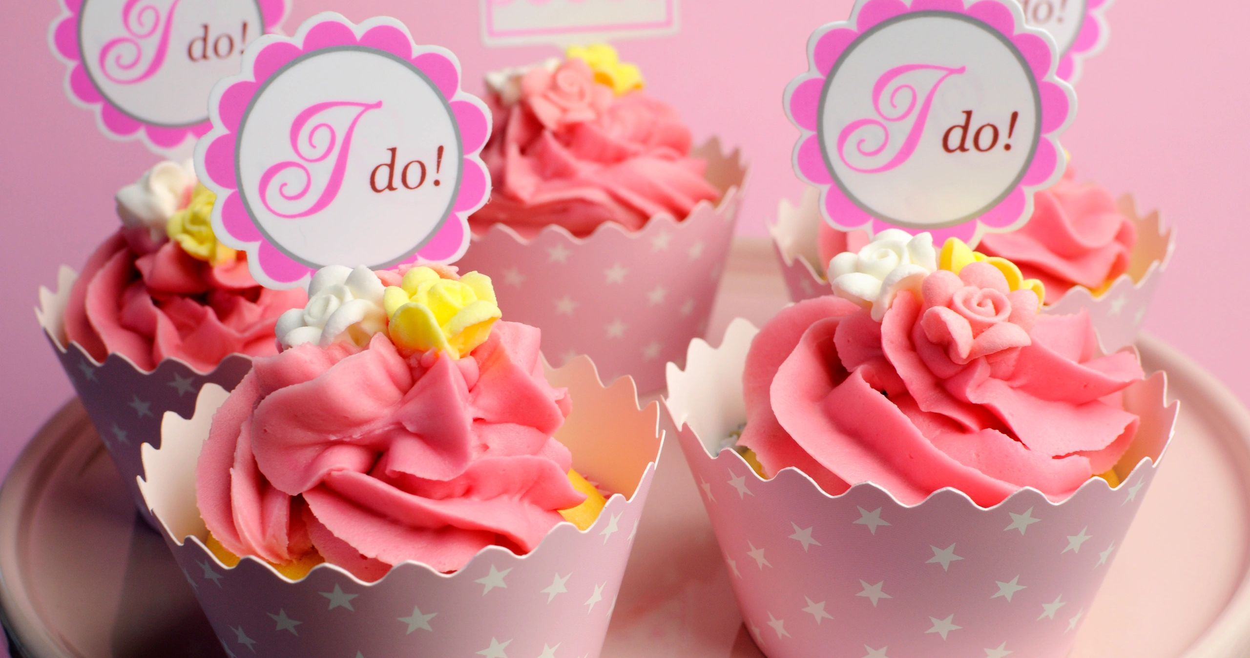Pink wedding-themed cupcakes with floral decorations.