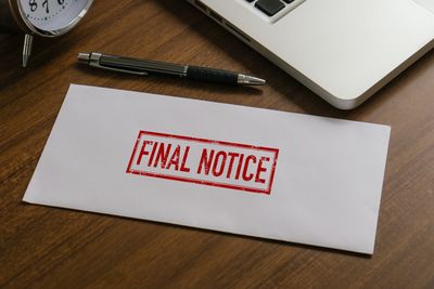 Envelope stamped with "Final Notice" on a desk with a pen and laptop.