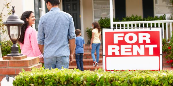 Family looking at a house with a For Rent sign.