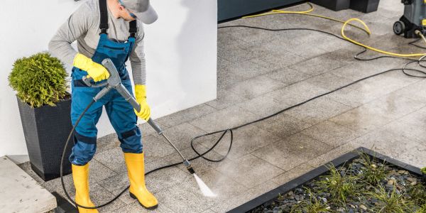 Person pressure washing outdoor pavement.