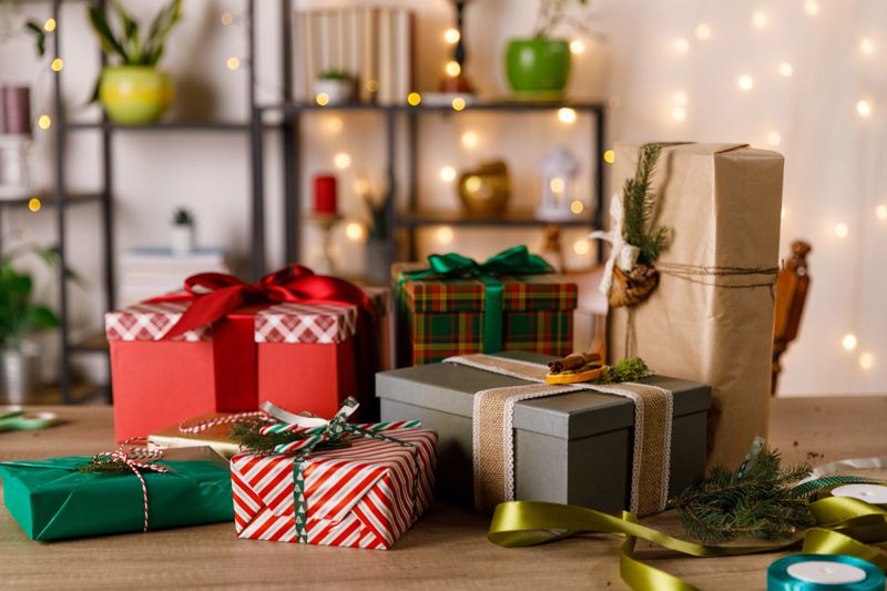Close up shot of variety of beautifully wrapped and decorated Christmas gift boxes stacked on a wooden table.