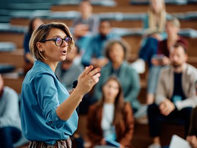 A woman presenting to an audience in a lecture hall.