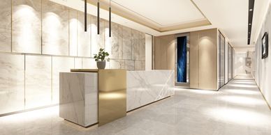 Modern reception area with marble and gold accents, bright lighting.