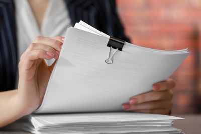 Person flipping through a thick stack of papers held by a binder clip.