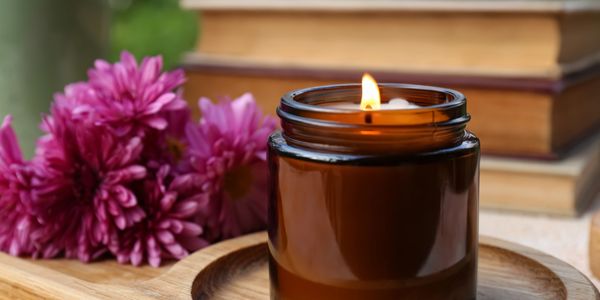 andle burning inside a bottle with flowers beside it,