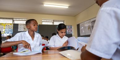 Students in white uniforms studying together in a classroom.