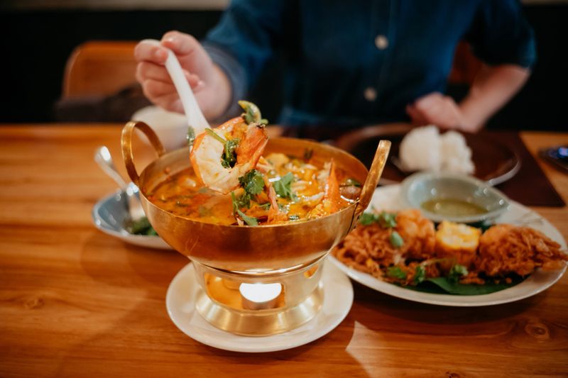 Young Asian woman eating traditional Thai cuisine, seafood Tom Yum Kung in a Thai fine dine restaurant