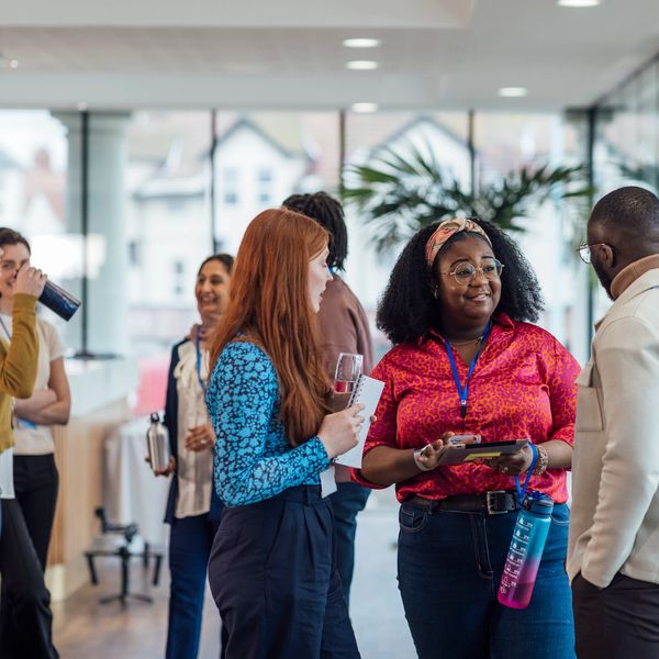 Diverse group of professionals networking and chatting at a modern office event.