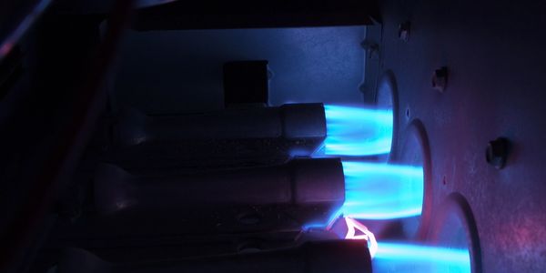 Flames leaving three burners and entering a heat exchanger.