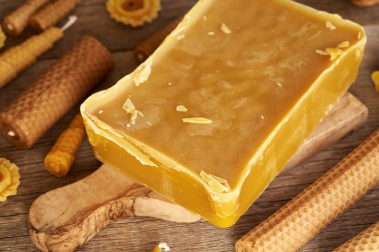 Block of beeswax surrounded by rolled and molded beeswax candles.