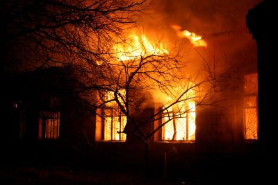 House engulfed in large flames at night.
