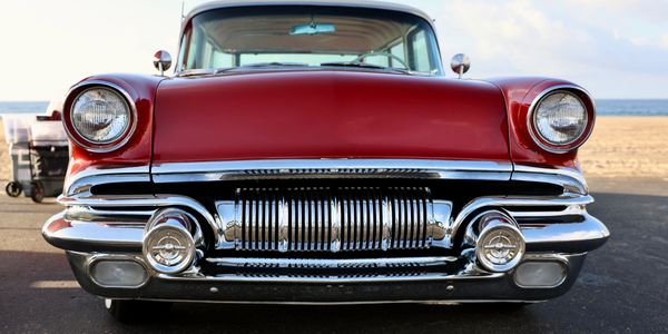 Front view of a classic red vintage car with chrome details.