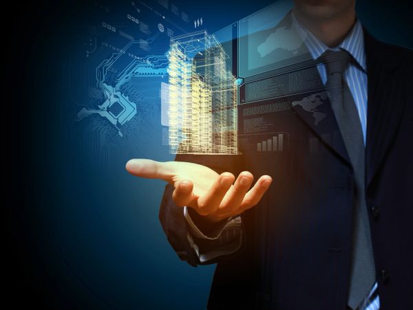 Businessman presenting a digital hologram of a building with data overlays.