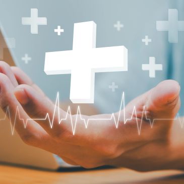 Hand holding a floating medical cross with heartbeat line graphics.