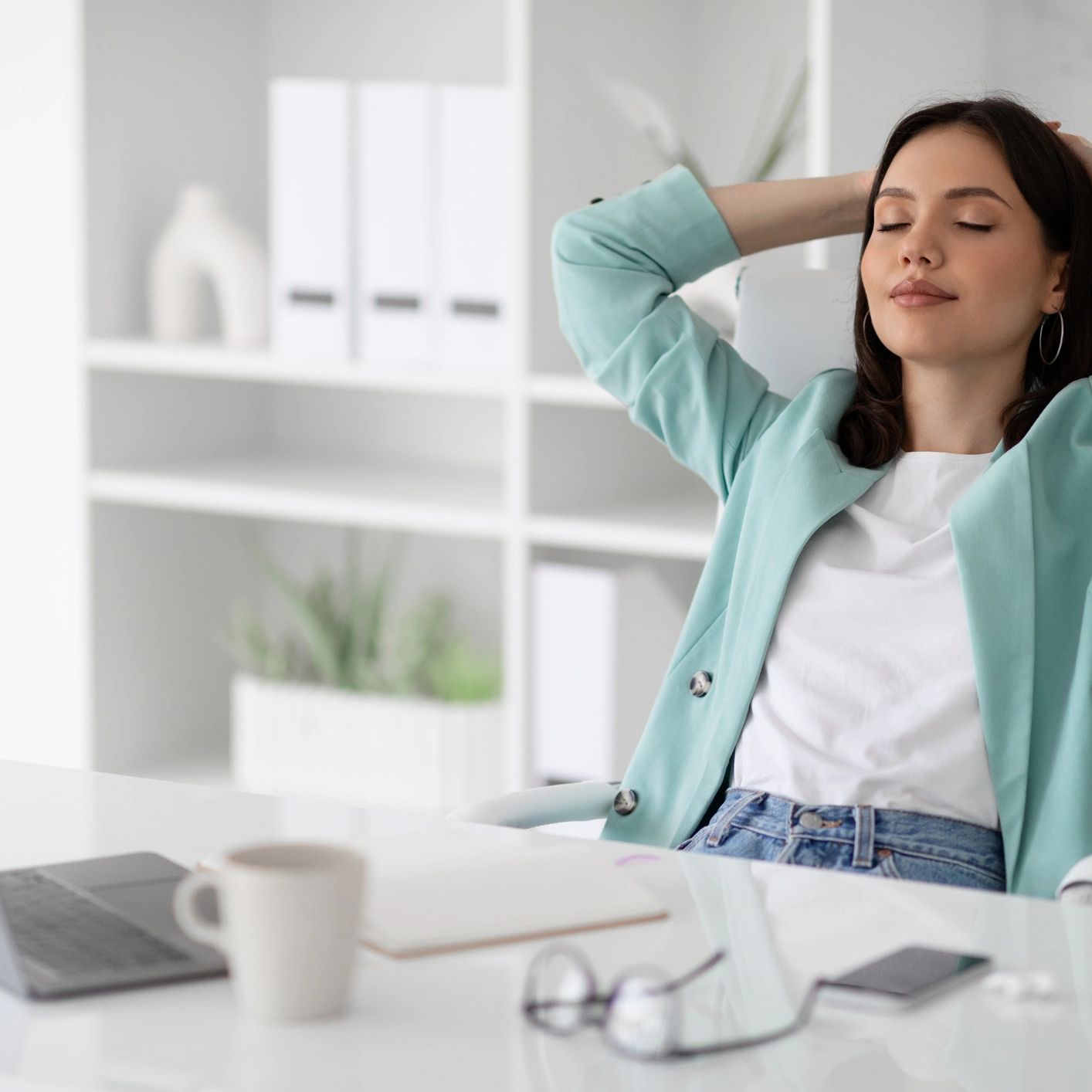 Woman leaning back at her desk with eyes closed, taking a calm break
