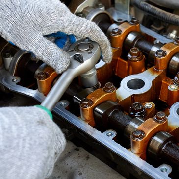 Person using a ratchet wrench to work on an engine component.