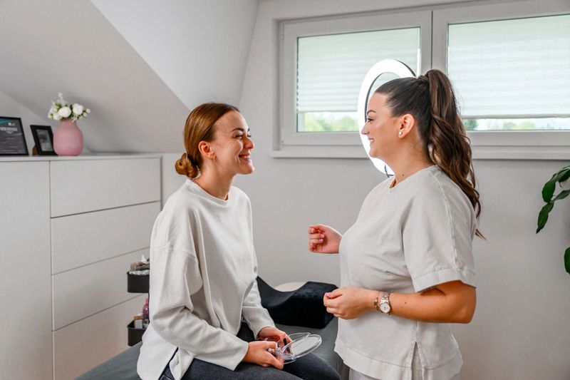 Female client having a conversation with a young female aesthetician before or after a beauty treatment.