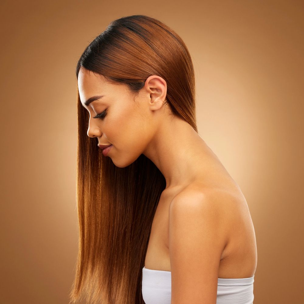 Profile of a woman with smooth, straight hair against a warm brown background.