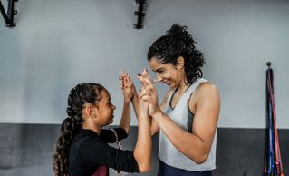 Woman and girl sharing a joyful moment during exercise.
