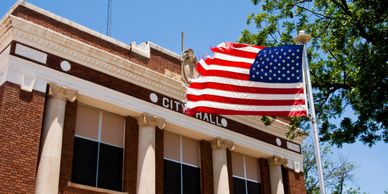 American flag waving in front of a city hall building.