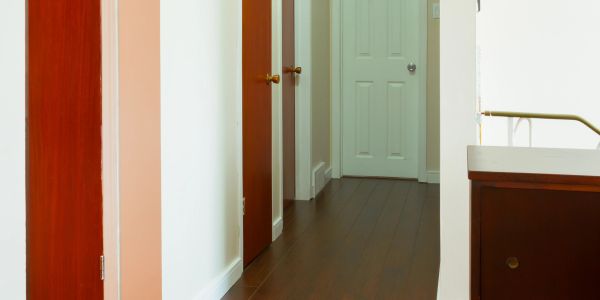 Empty hallway with wooden doors and flooring.