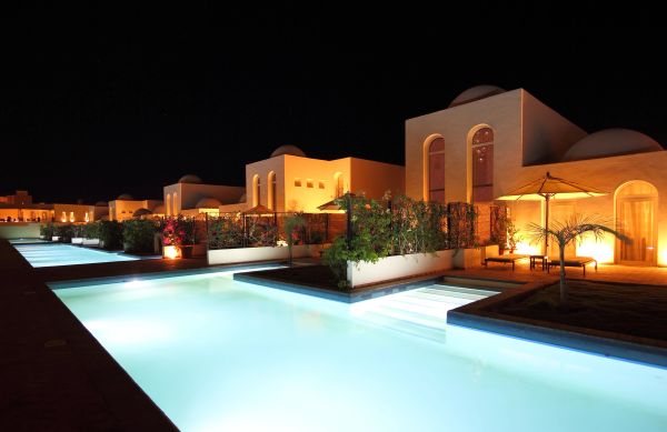 Nighttime view of illuminated modern villas with pools.