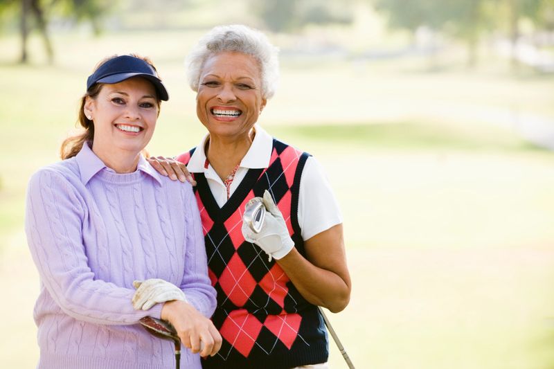 Female Friends Enjoying A Game Of Golf Together Smiling To Camera