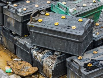 Stack of old, damaged car batteries with corrosion and leakage.