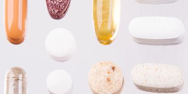 Various types of pills and capsules on a light surface.