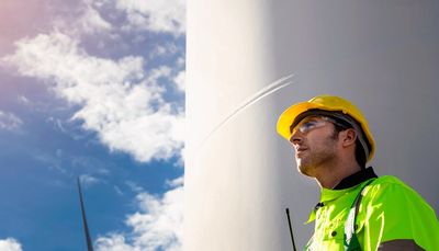 Engineer inspecting a wind turbine on a sunny day.