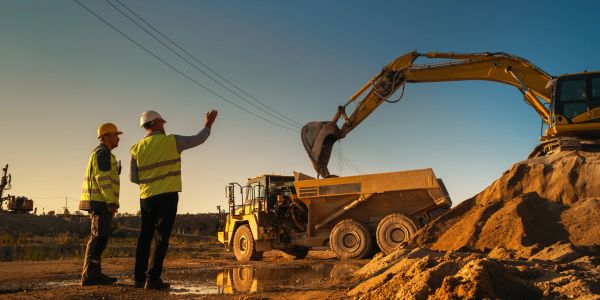 Construction workers oversee excavation and loading.