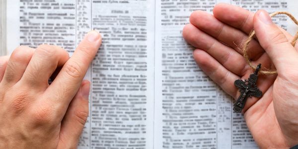Person reading a book holding a cross.