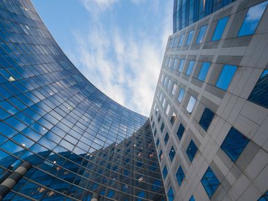 Looking up at modern glass and concrete skyscrapers against a blue sky.