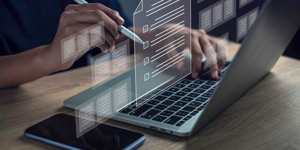 Person using a stylus and laptop to manage digital checklists and documents.
