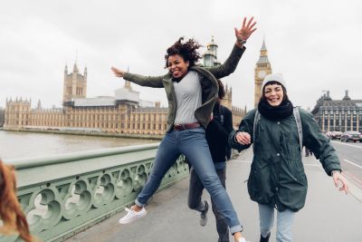 Happy friends jumping on a bridge in London.