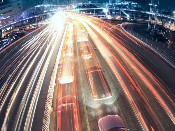 Long exposure shot of cars creating light trails on a busy city highway at night.