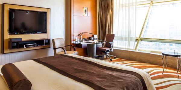 Modern hotel room with large bed, desk, and big window.