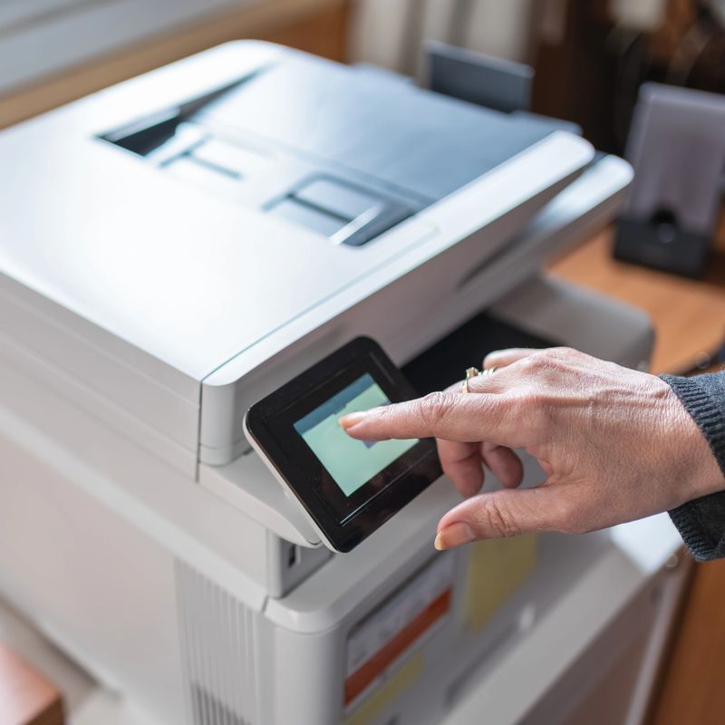 Woman operating a printer while teleworking from home remotely