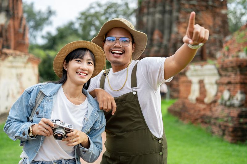 Asian couple best friends traveller  having fun during vacation in temple of the Ayutthaya buddha in Thailand.