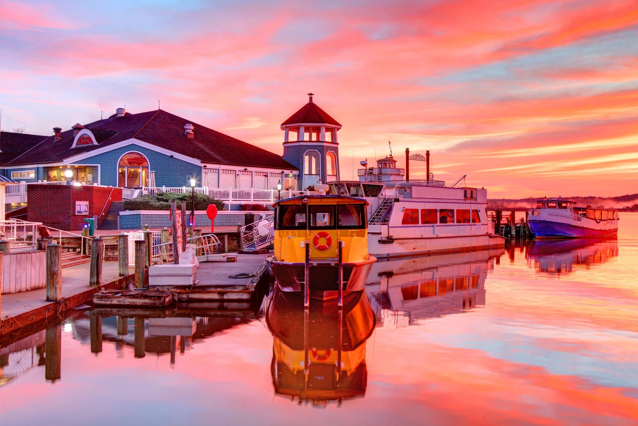 Boats docked at a marina under a vibrant sunset sky.