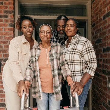 Four generations of a family standing together outside a house.